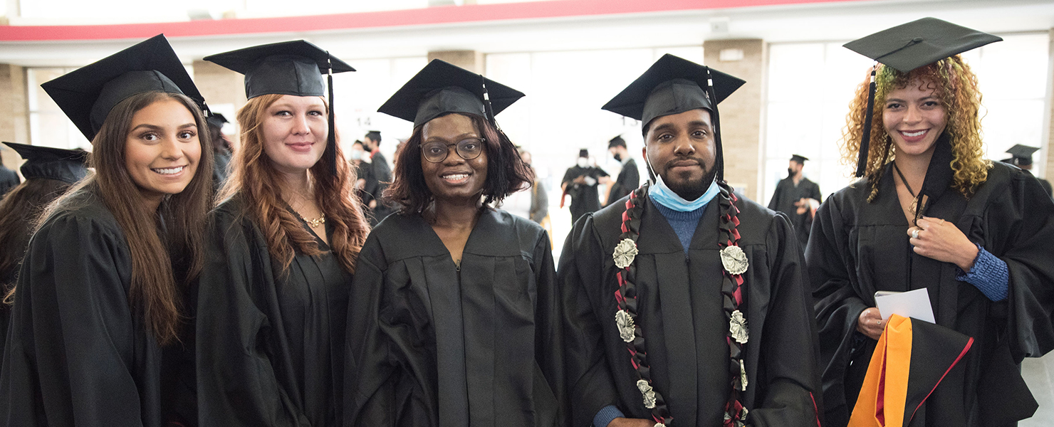 two students celebrating graduation in front of alumni donor wall