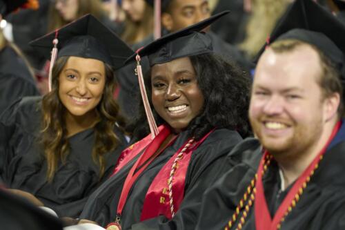 three students smiling during commencement