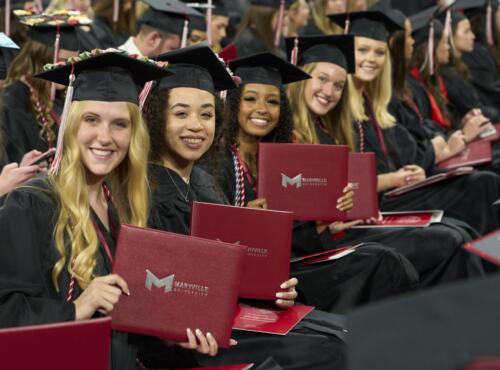 several students holding diploma book