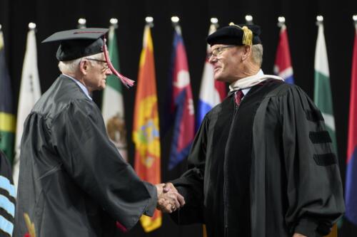 board member congratulating 83 year old graduate