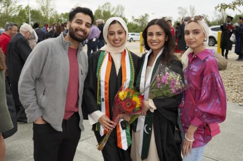 student posing for pictures with friends and family outside after commencement