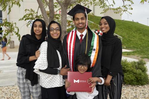 graduate flanked by friends and family