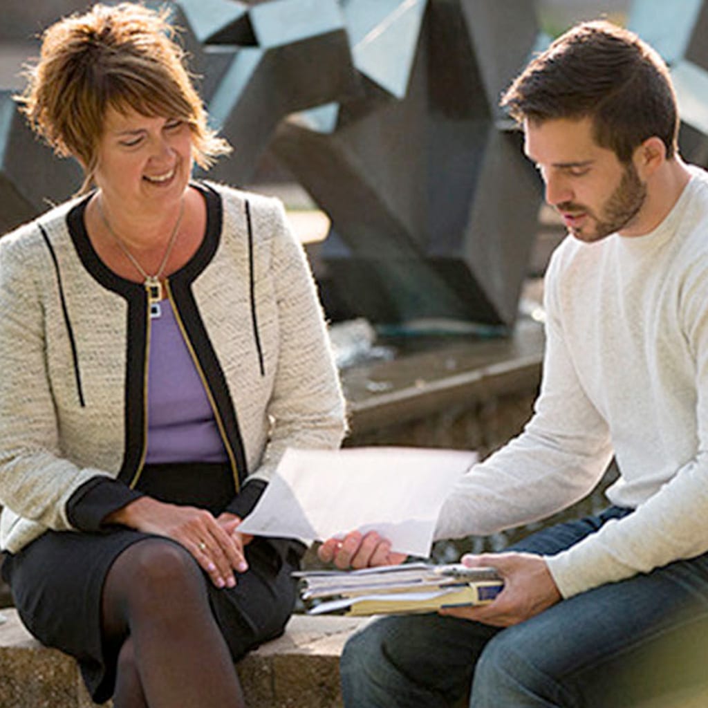 professor helping student outside on the quad