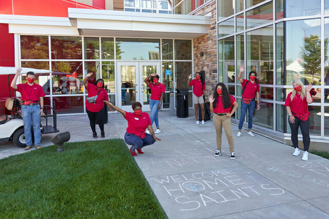 students in front of residential hall waving