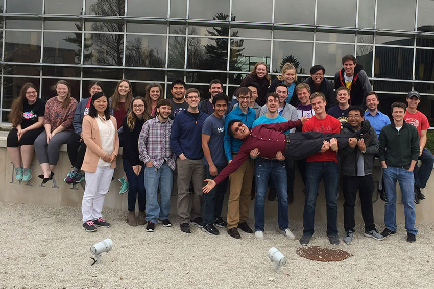 Students carrying teacher and posing for photo