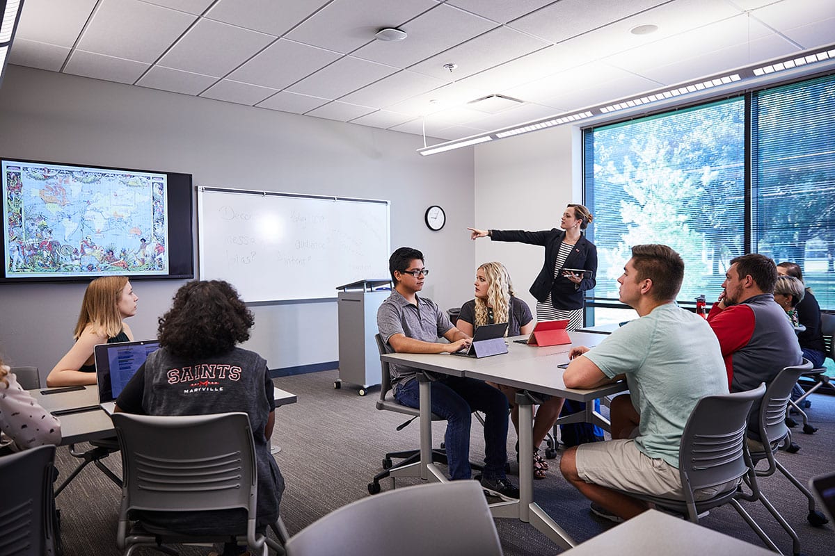 Professor in front of white board teaching students