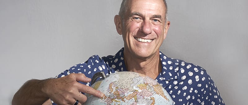 Professor Kevin Stokes pointing at a globe